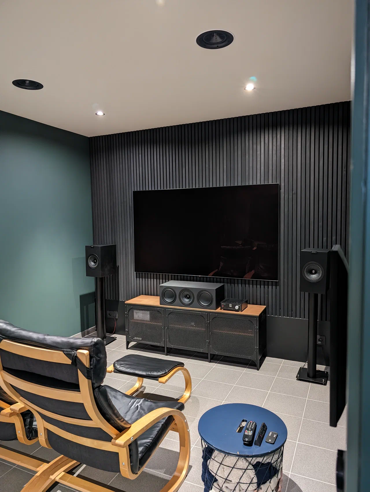 Two seats in front of a 77" tv hung on a wall with wood slats