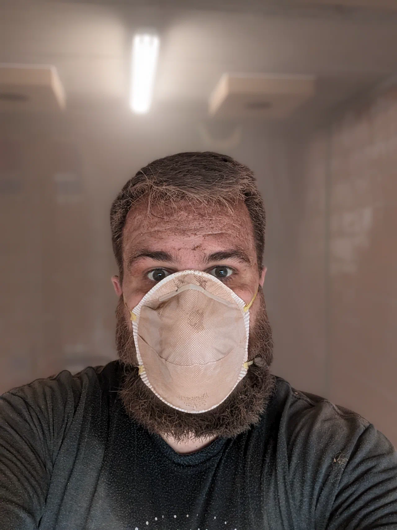 A very dusty man with a beard and a dust mask