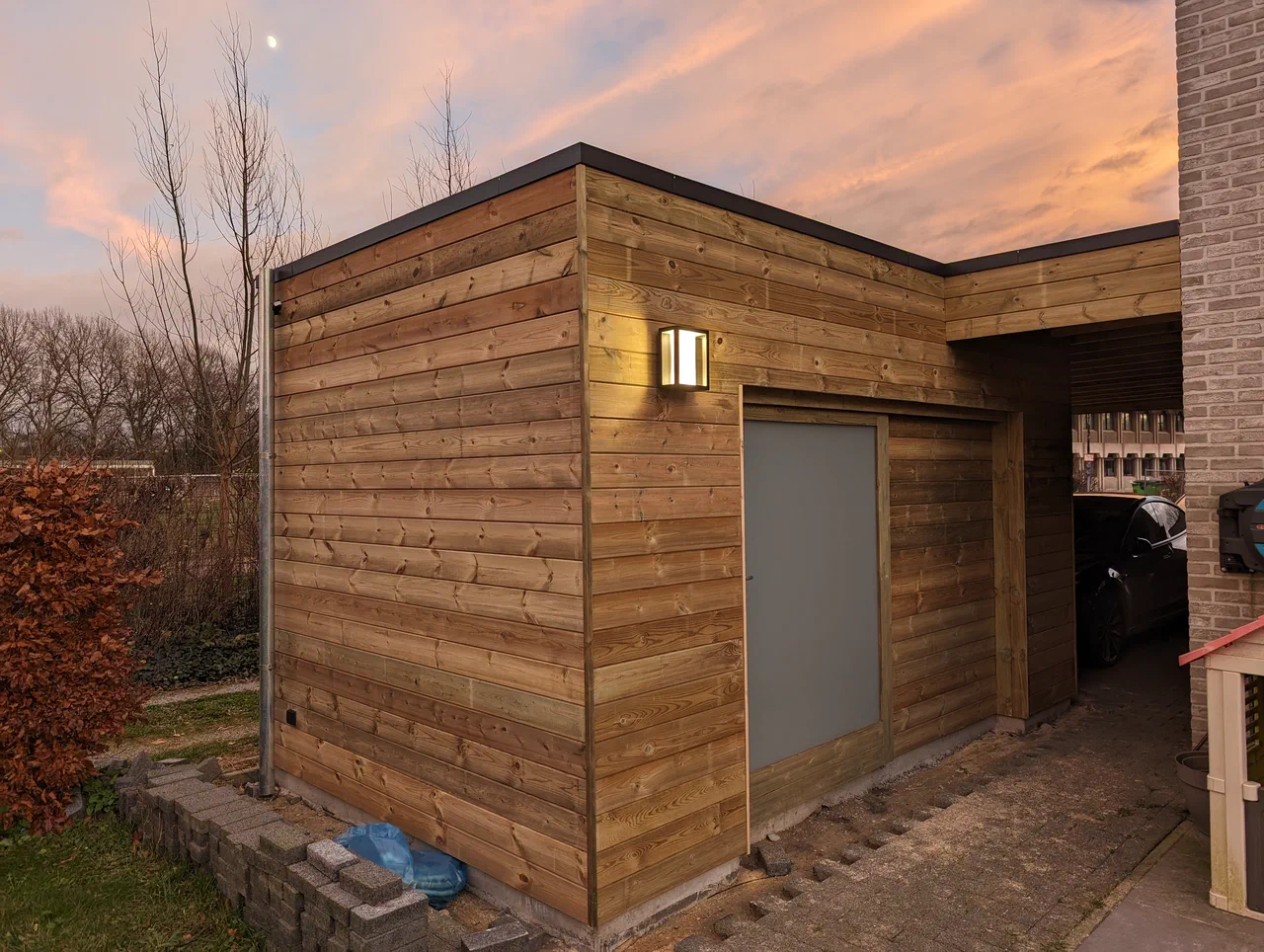 A wooden garden shed with a carport attached to a semi-detached house