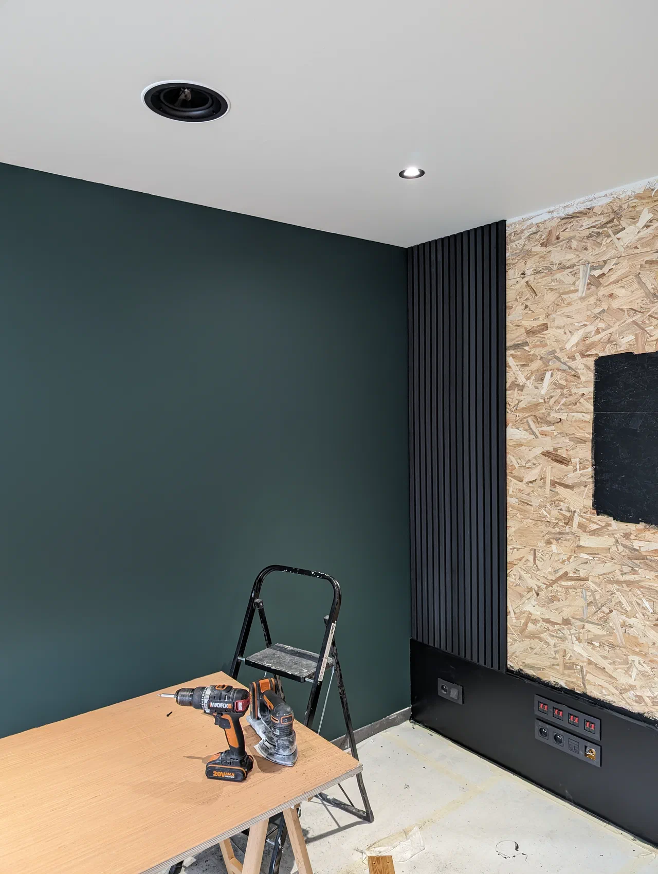 OSB wall getting wood panels hung, other wall painted green