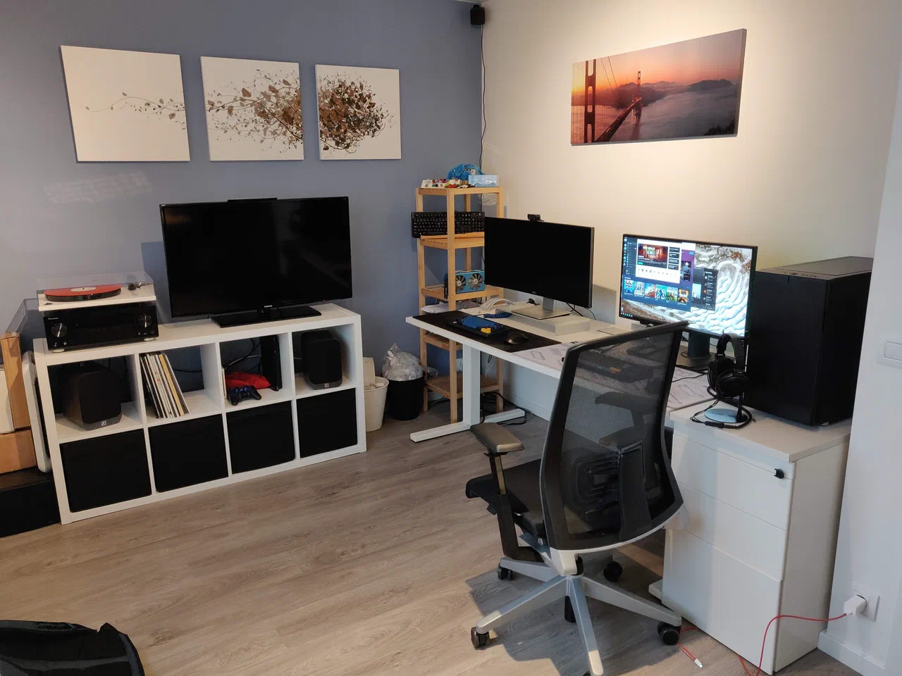 A cabinet with a tv on top and a desk with two monitors and a desktop pc